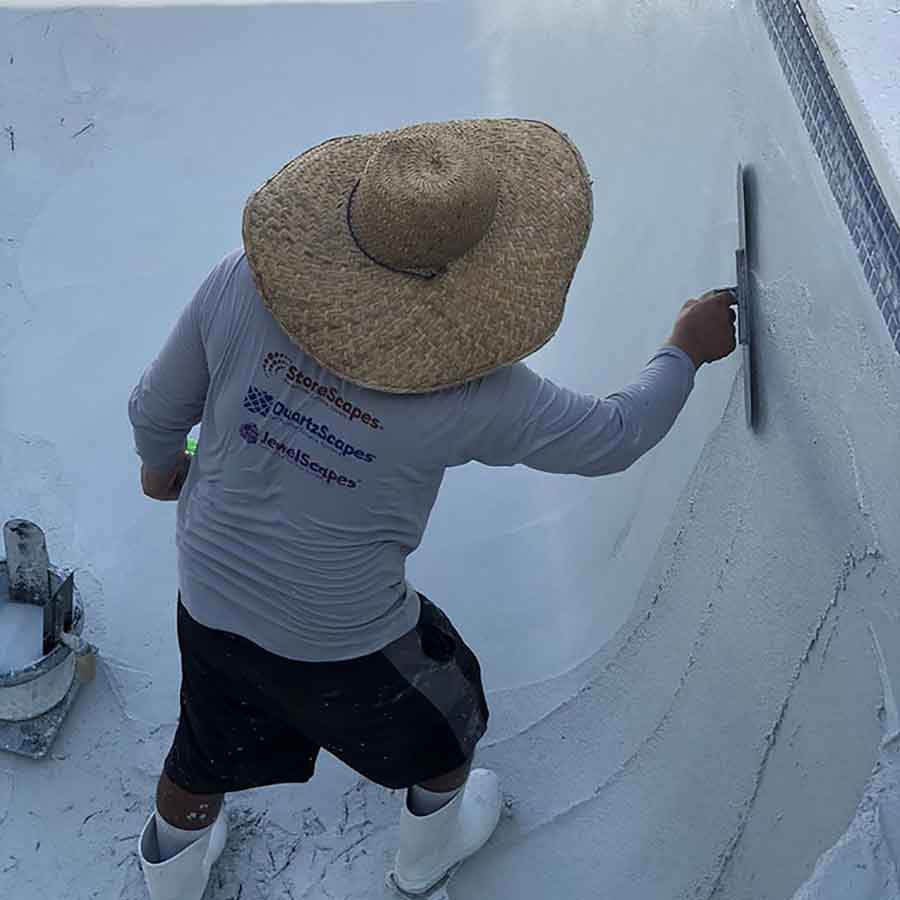 A Chief Pools crew member hand-troweling fresh plaster inside a pool shell